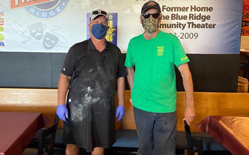 Blue Jeans Pizza and Pasta Factory owner Ken Brenneman, left, and Blue Ridge Community Theater (BRCT) Emeritus Joe Webb stand before a wall built by the theater’s set builders for the restaurant.
