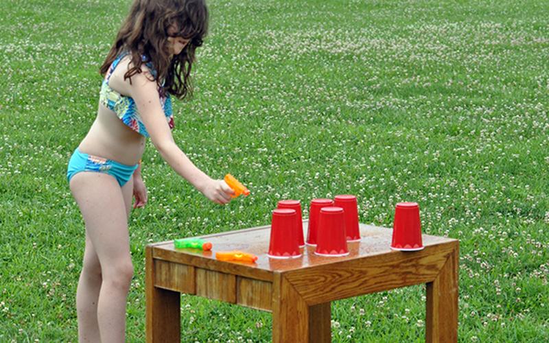 Violet Miller tries her luck at shooting red solo cups over with a water gun during the Fannin Recreation Center‘s summer camp, Wednesday, July 8.