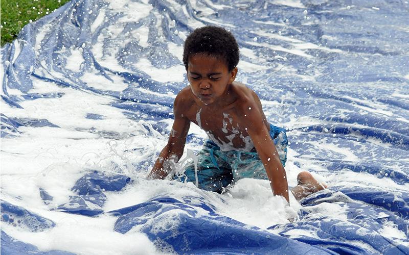 Jamel Johnson dives down the slip-n-slide at the Fannin Recreation Center’s summer camp, Wednesday, July 8.