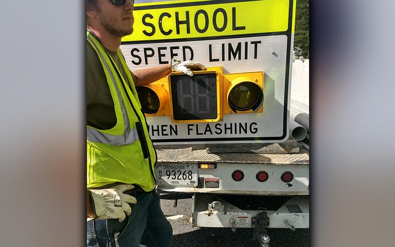 A worker from Nabco Electric is shown with one of the flashing school zone lights installed on Highway 68 in front of the entrance to Copper Basin schools.
