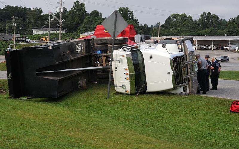 A Lance Trucking company dump truck lies on its side just off Windy Ridge Circle after the dump bed struck a power line Friday morning. Power was knocked out to over 800 customers. The power pole snapped when the truck pulled down a line can be seen in the background.