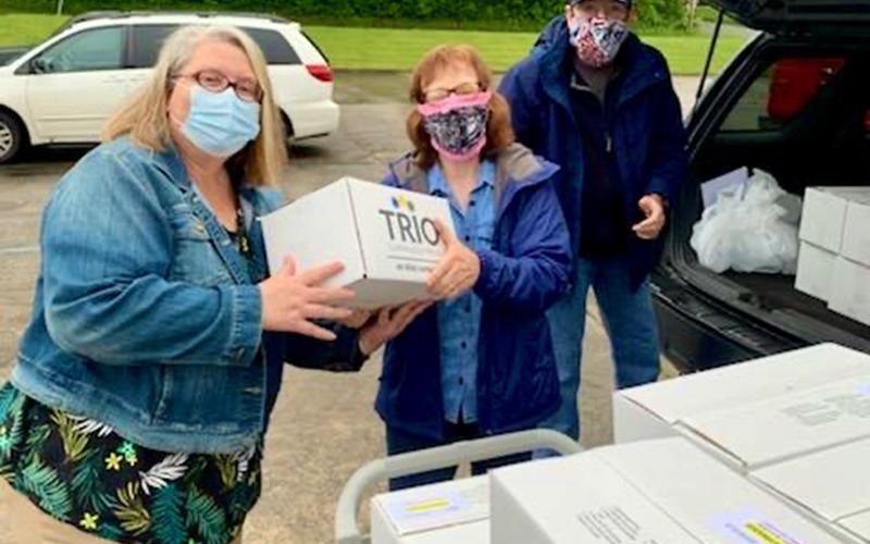 Meals on Wheels Coordinator Pam Godfrey, left, is shown passing off a box to Feed Fannin volunteer Brenda McKee. The boxes are filled with meals that were delivered to homebound seniors around Fannin County. Charlie McKee is shown in the background waiting for another box.