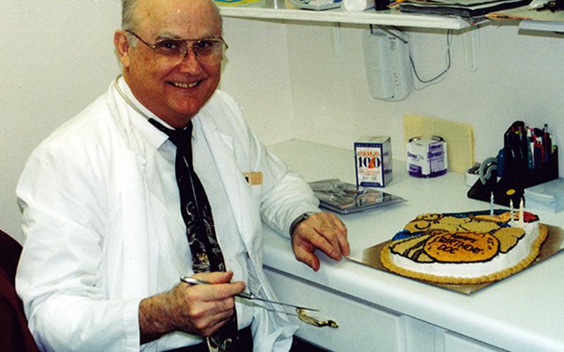 The late Dr. James Haymore III is shown in his office smiling before cutting his birthday cake from years past.