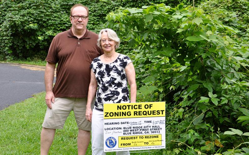 Gene and Margaret Middleton stand behind the City of Blue Ridge’s Notice of Zoning Request sign, located before the potential townhome and designer cottage community, which is just feet from their residence.