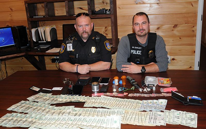 Detective Cory Collogan, left, and Chief Mike Earley of the McCaysville Police Department are shown with the cash, drugs and other assorted items seized Saturday night in connection with the arrest of Brian Joseph Martell.