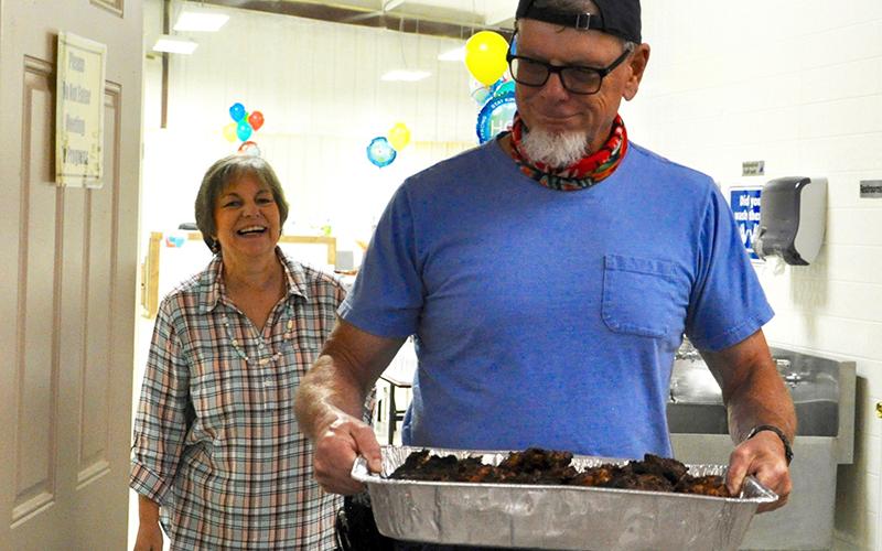 A volunteer appreciation lunch was hosted by Fannin County Family Connection to show appreciation for their volunteers, on the anniversary of the move-in day at their current facility. Jim Yacavone carries in a pan of grilled chicken while Executive Director Sherry Morris smiles wide.