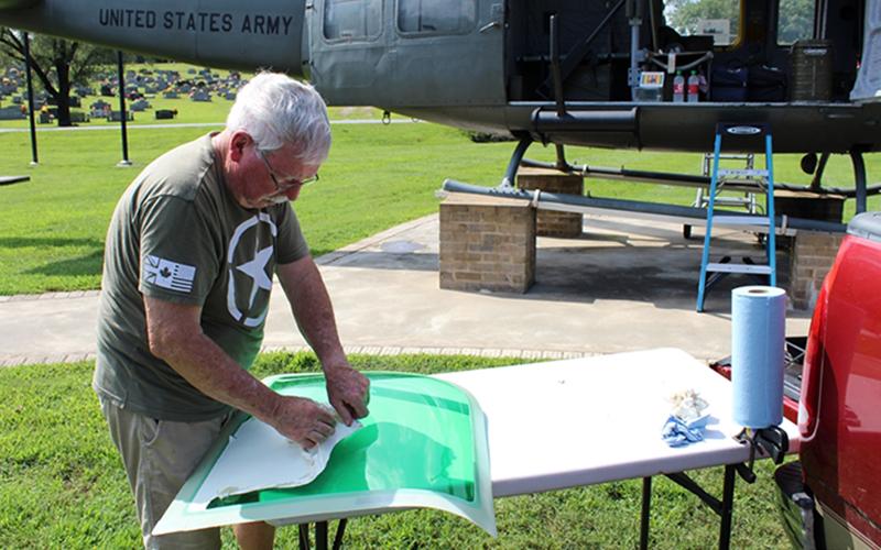 Veteran Rod McIntyre is shown peeling off the protective spraylat coating of the new greenhouse window for the Huey helicopter that was recently damaged.