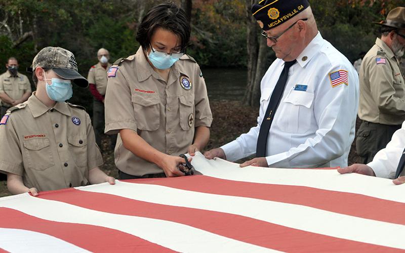 Boy Scout Jefferson Lewis cuts the stripes of an American flag while North Georgia Honor Guard member Richard Crosley holds the flag during a Flag Retirement Ceremony Tuesday, October 20. The ceremony was conducted at Ron Henry Horseshoe Bend Park by honor guard members and Epworth Scout Troop 32.