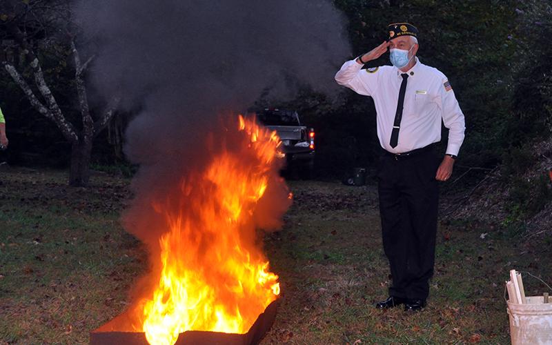 Veteran Steve Strickland renders a salute while American flags are retired Tuesday, October 20.