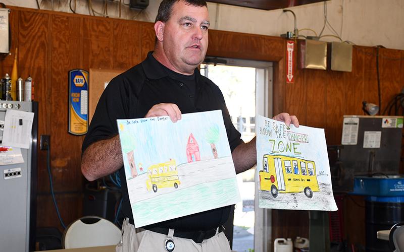 Fannin County School System Transportation Director Denver Foster displays two of the Fire Safety Week Posters from Fannin County that will move on in the state’s competition.