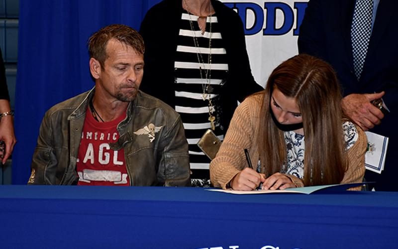 Fannin County Middle School student Jacee Fain signs her Realizing Educational Achievement Can Happen (REACH) contract as her father, Nathan Fain, looks on during the REACH Signing Ceremony Wednesday, October 21.