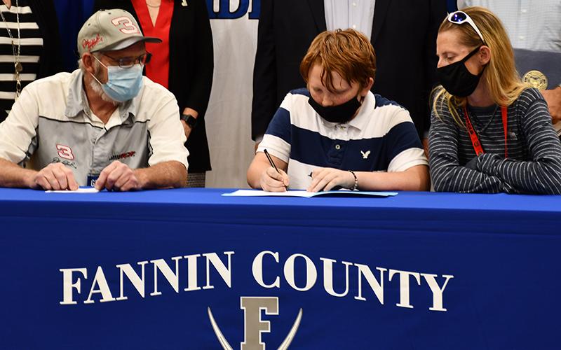 Fannin County Middle School student Rilee Flowers signs his Realizing Educational Achievement Can Happen (REACH) contract as his parents, James and Melissa Flowers, wait to sign their own agreements during the REACH Signing Ceremony Wednesday, October 21.