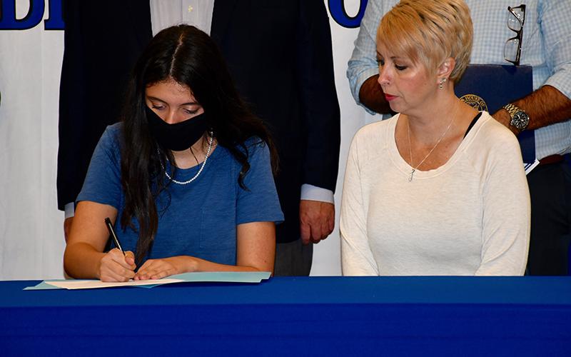Fannin County Middle School student Abigail Ridings signs her Realizing Educational Achievement Can Happen (REACH) contract with her mother, Kelly Davis, as representatives from across the state celebrate each student’s commitment