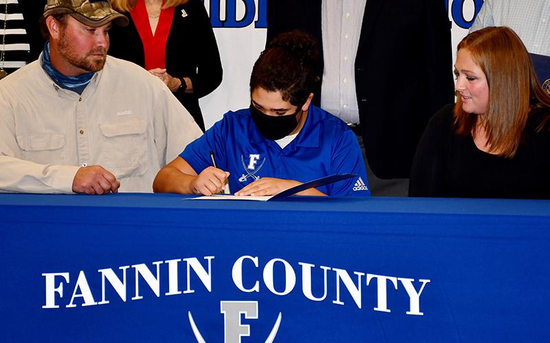 Fannin County Middle School student Nolen Urrutia joins the sixth class of Realizing Educational Achievement Can Happen (REACH) scholars as he signs his commitment Wednesday, October 21. He is joined by Blake and Brittany Stites.