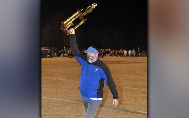 Fannin Rebel football Head Coach Chad Cheatham smiles as he hoists the Region 7AA Championship trophy after Fannin’s 55-7 win over Dade County Friday, November 20.
