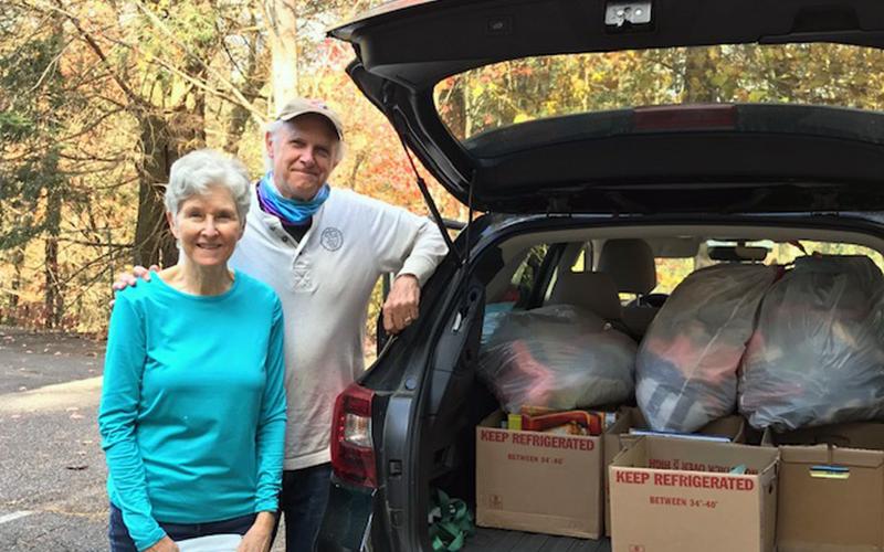 The Craddock Center volunteers Milly and Steve Hastings pack their car in preparation of delivering knitted hats and new books to children Friday, November 13.