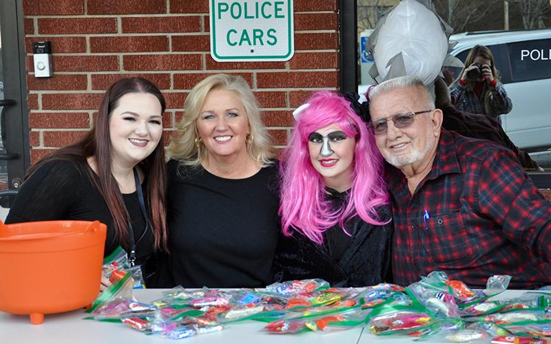 Kaylee Robertson, from left, Judy Earley, Madison Earley and City of McCaysville Mayor Thomas Seabolt smile while passing out candy in front of the McCaysville Police Department Saturday, October 31.