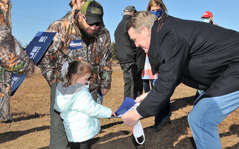 Georgia's senior U.S. Senator David Perdue brought his Win Georgia, Save America campaign to Fannin County last Tuesday, December 8. Perdue, who is seeking re-election in the January 5 runoff, quoted Ronald Reagan when he told supporters, "Freedom is just one generation away from extinction." Here, he greets a member of the next generation, Khloe Robinson, as her father, Jeremiah, looks on.