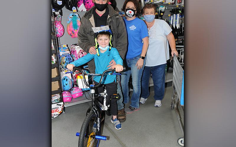 Shop With A Cop counts on many volunteers to help make the annual program a success, such as Fannin County Chief Tax Appraiser Dawn Cochran. She is shown, third from left, with Levi Lacy who is all smiles as he shows off his brand new bicycle. Jason Long and Merilee Bennett were also there when Lacy made his choice during the event Saturday at the Blue Ridge Walmart.