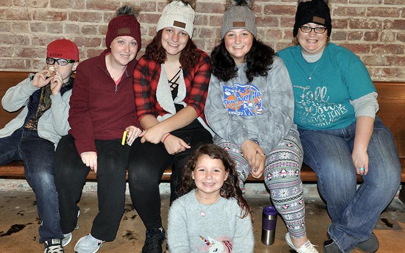 Braden Hamilton, KB Hamilton, Valere Cash, Bristol Cash, Abby Cash and Kendra Cash, from left, found a spot inside the Riverwalk Shops to take a load off before the Light Up McCaysville tree lighting Friday, November 27.