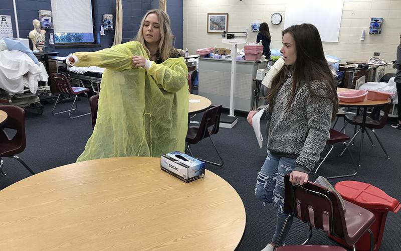Fannin County High School student Ella Richardson, left, is shown being evaluated by her fellow student, Karly Waters, on the proper application and removal of personal protective equipment in Healthcare Science teacher Anne Gibbs’ Patient Care Fundamentals course.