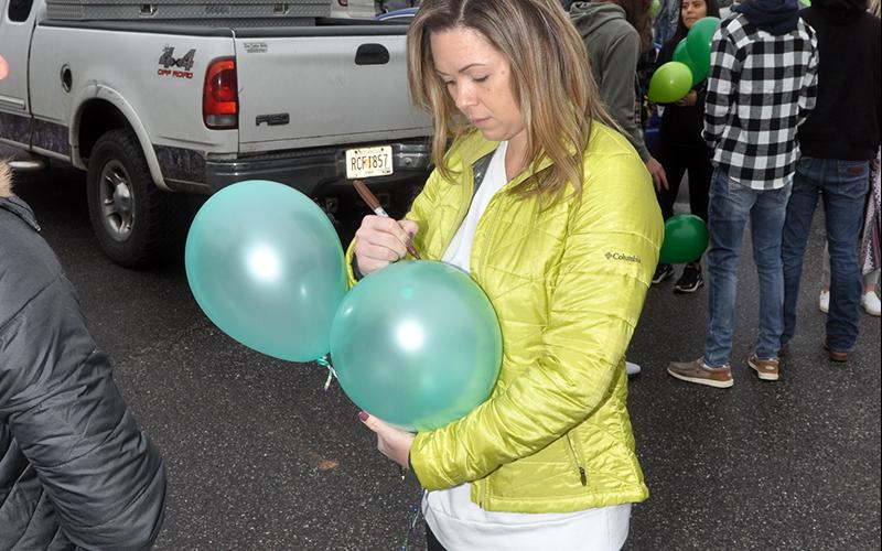 Samantha Bailey writes a message on one of her balloons before they were released Friday, January 22. She was among the many friends and family members of Sydnie Jones who gathered in the parking lot of the First Baptist Church of Blue Ridge to honor Jones' life.