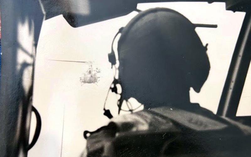 Rod McIntyre flew several missions via helicopter during his service in the Vietnam War. He managed to take a photo, shown above, from behind the pilot of a helicopter as his crew descended into the landing zone using a “daisy chain” technique.