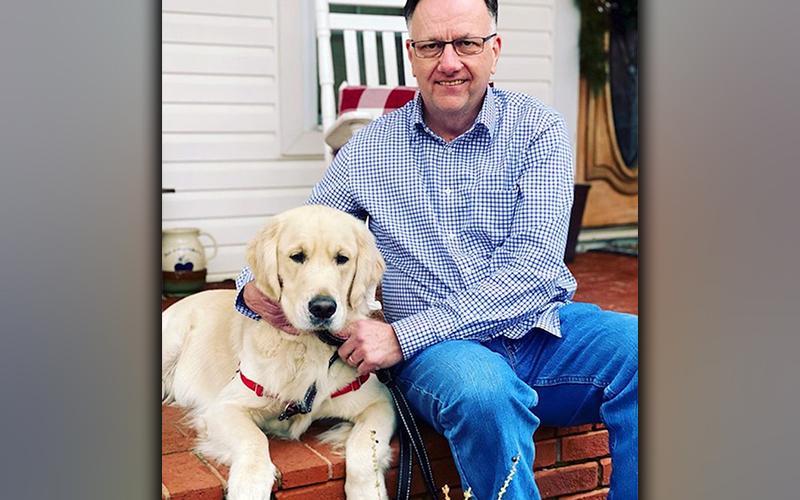 Charlie the Therapy Dog is shown with one of his favorite people, Reverend Asa Dockery.