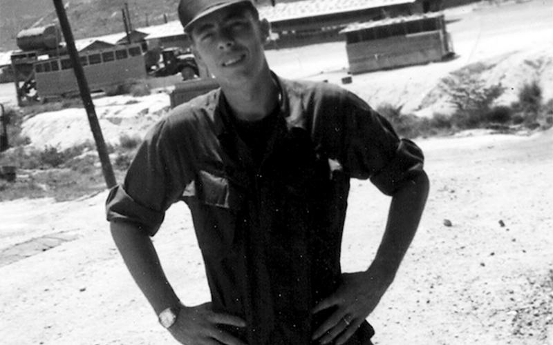Army veteran Paul Hunter is seen at a fuel dump with the mountains of Quinn Yan, Vietnam, in the background.