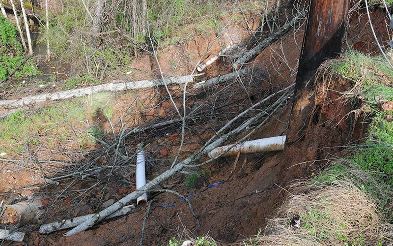 A City of Blue Ridge water line lies broken below a power pole, both affected by a washout early Friday morning off Bullen Gap Road.
