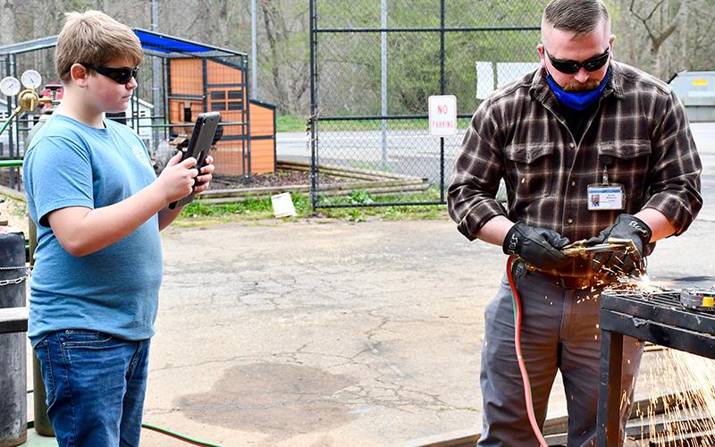 East Fannin Elementary School student Morgan Bennett had the opportunity to learn more about what CTAE has to offer at Fannin County High School Friday, March 19. Here he is shown documenting welding teacher Terry Flowers as he cuts a piece of steel.