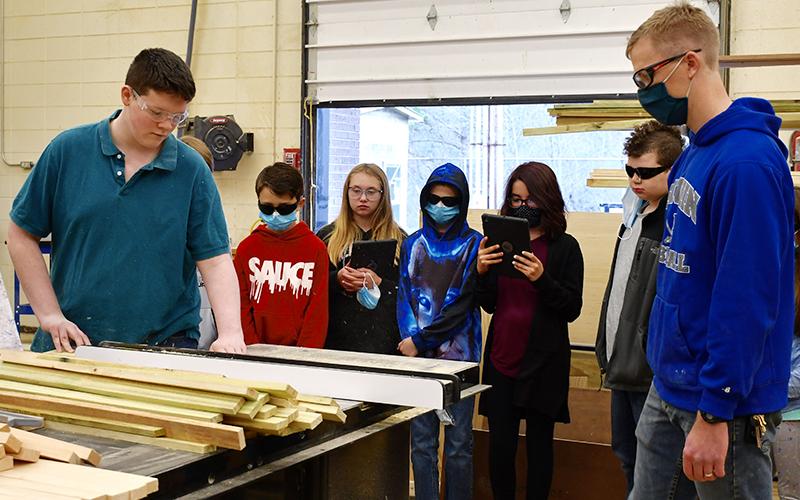 Fannin County High School construction student Trenton Yohn demonstrates the use of a table saw for East Fannin Elementary School students as construction teacher Daniel Stewart watches on. East Fannin students shown are, from left, Brady Cole, Venice Oliver, Rylee McCalley, Izzy Torres and Carter Campbell.