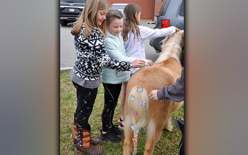 East Fannin Elementary School third grade students Melanie Padgett, left, and Sophie Price pet a pony during the Fannin County High School FFA Chapter’s Ag Day.