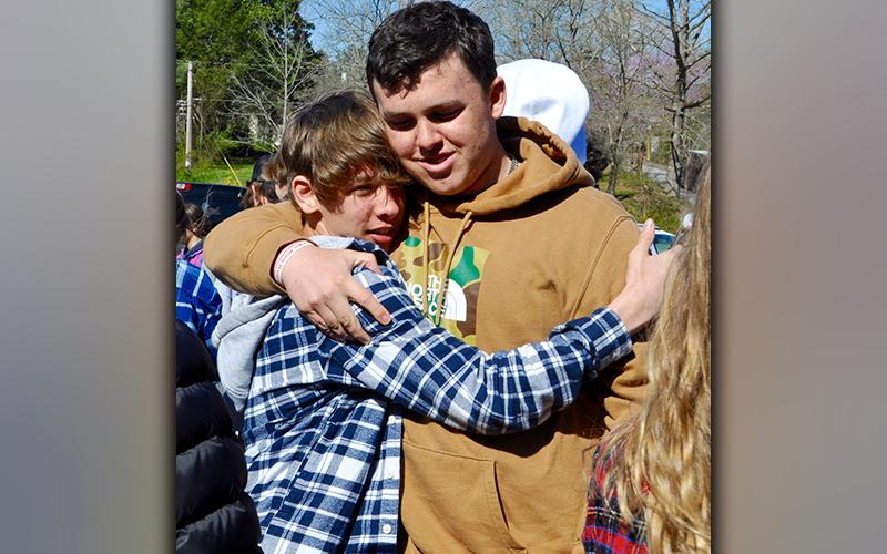 Braden Taylor, left, and Case Holloway embrace one another after releasing balloons for friend Shane Adrian “Dewey” Derreberry Thursday, April 1.