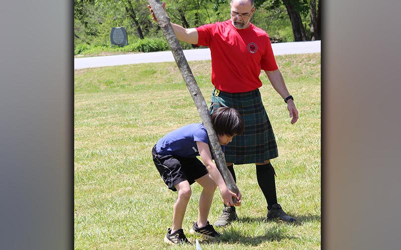 Boy Scout James Grubb learns the caper toss with the help of Tom Lawrence at Troop 32's Highland Games Saturday, May 1.