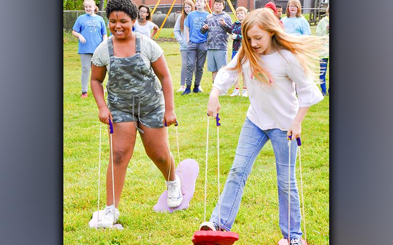 Emma Chambers, left, and Josalyn Deal race each other while sporting very large feet during West Fannin Elementary School’s field day.