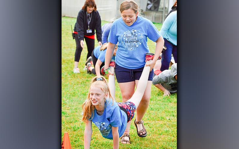 Lyla Strange holds on to friend Lana Hicks’ feet while they wheel-barrel race during West Fannin Elementary School’s field day.