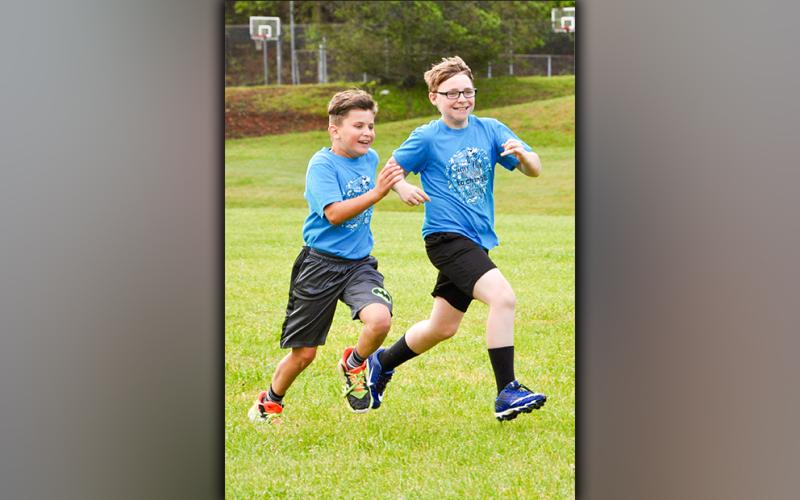Reed Puckett, left, and Devon Hasker are all smiles Thursday, May 13, as they race themselves and peers during field day at West Fannin Elementary School.