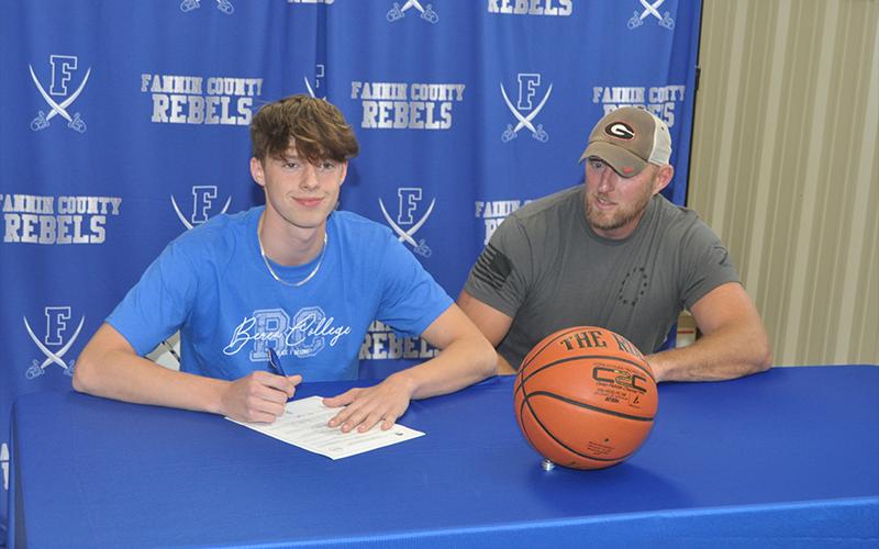 Kaeden Twiggs, left, smiles with his father Josh Twiggs after he signed his scholarship to play basketball for the Berea College Mountaineers. Friends and family gathered at the Fannin Recreation Department Wednesday, May 12.