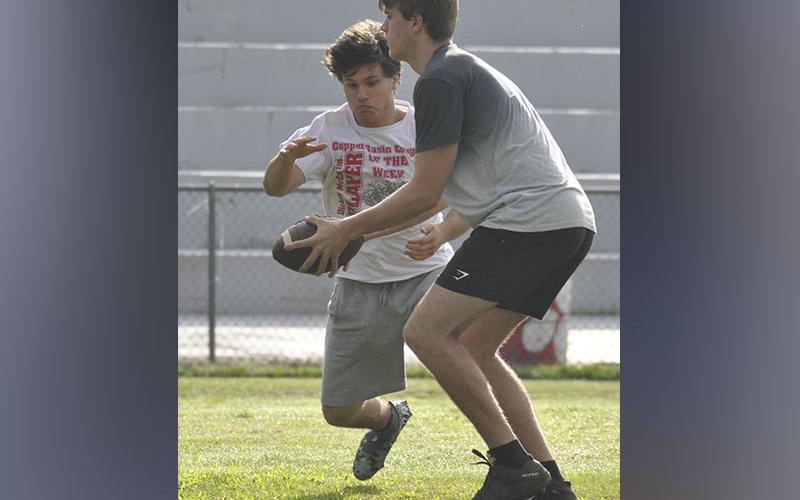 Quarterback Joe Boggs, right, hands the ball off to runningback Sebastian Balilies during the Cougars’ football practice Thursday, June 10.