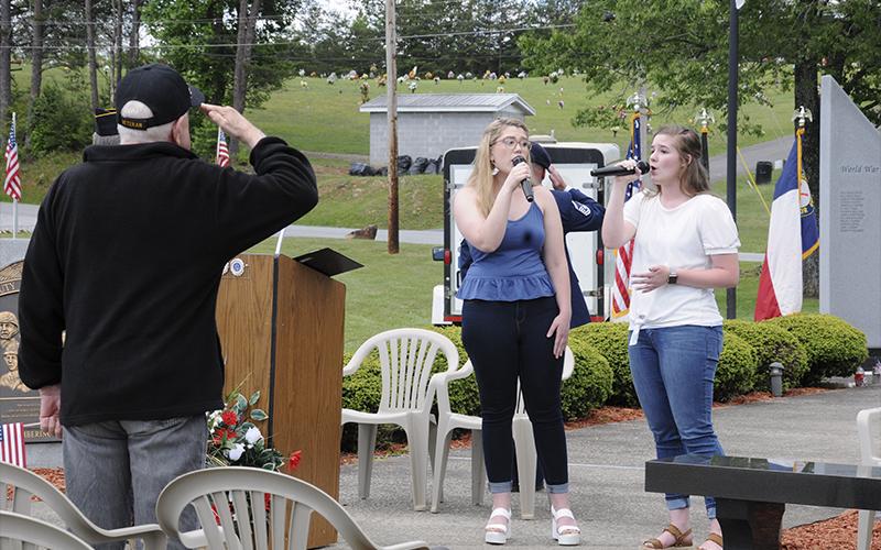 A veteran salutes as Mari McCray and Emma Thomas (right) sang the Star Spangled Banner to open the Memorial Day Ceremony at Veterans Memorial Park in Blue Ridge Monday, May 31. A large crowd gathered to remember the men and women who have  paid the ultimate sacrifice for freedom. McCray and Thomas represented Mountain Area Christian Academy, where McCray just graduated and Thomas is a student.
