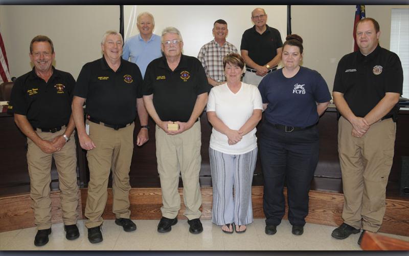 Darrell Payne was honored at the Fannin County Board of Commissioners meeting Tuesday, June 23, when he officially announced his retirement after 38 years with the county Emergency Medical Service. Shown after Payne was presented a gift are, from left, front, Fire Chief Larry Thomas, Emergency Management Agency Director Robert Graham, Payne and his wife Tammy, new EMS Director Becky Huffman, outgoing 911 Director Patrick Cooke, and, back, Post 1 Commissioner Johnny Scearce, Commission Chairman Jamie Hensley