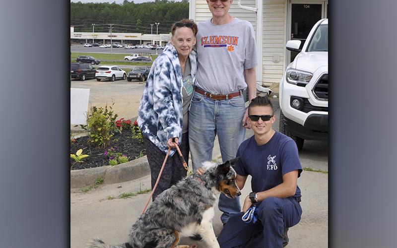 Kathy and Pete Kaup, back, waited anxiously for the rescue of their dog, Finn, after he had gotten stuck on a dirt cliff next to their home. Channing Johnstone kneels after returning Finn back to his owners Wednesday, June 2.