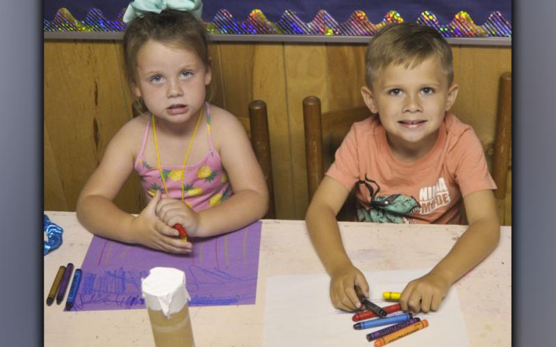 Kreidynce Cook, left, and Brady Reeves take a break from coloring to smile for a photo during McCaysville Gospel Tabernacle’s Vacation Bible School Tuesday, July 13.