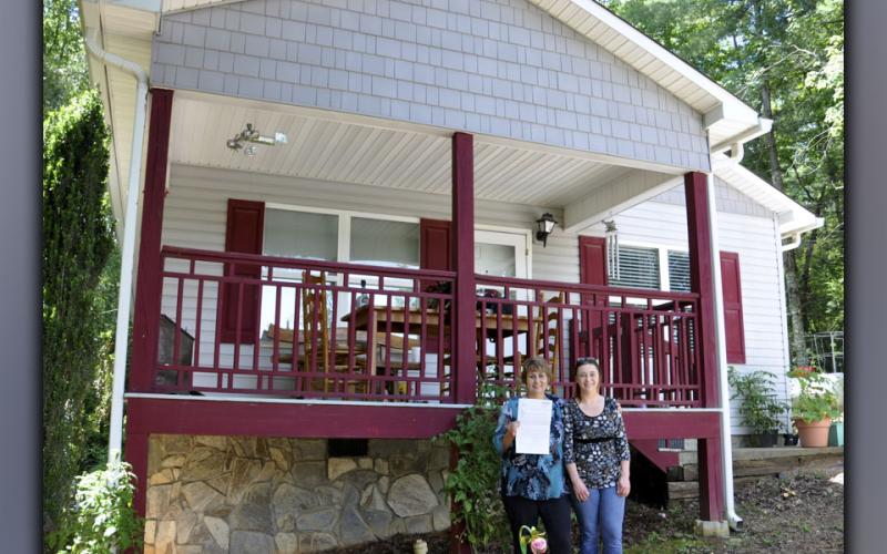 Gloria Ensley stands, deed to her home in hand, with her daughter, Ericia Almond.
