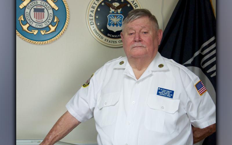 Retired United States Coast Guard veteran Gerald “Chief Mac” McMillen stands before the U.S. Coast Guard emblem at the Fannin County Veterans Museum.