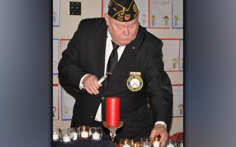In this photo from 2018, retired U.S. Coast Guard veteran Gerald McMillen lights candles of remembrance during a Veterans Day ceremony at West Fannin Elementary School.