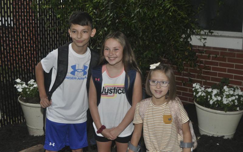 Levi Thomas, left, Jayden Miller, middle, and Allie Thomas put on big grins as they enter West Fannin Elementary School for the first day of classes Friday, July 30.