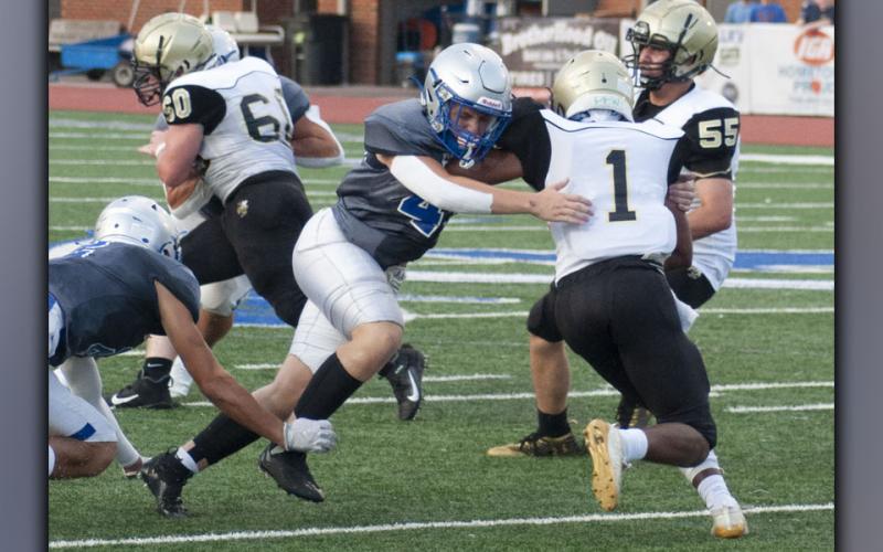 Cade Sands (49) fights through the Hayesville offensive line to bring down the Yellow Jacket quarterback during the Rebels’ scrimmage Friday, August 13. Sands had a solid game on both sides of the ball.
