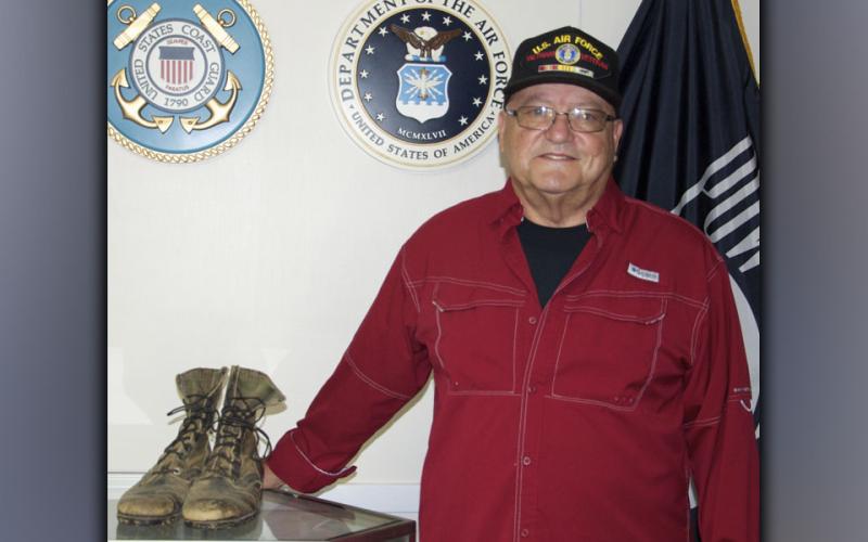 U.S. Air Force veteran Richard Crosley stands beside a pair boots he wore during his service.